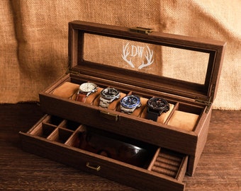 May include: A wooden watch box with a glass top and a drawer. The box has a deer antler design engraved on the glass. The box is open and there are five watches inside.