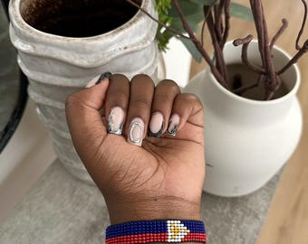 Puede incluir: Una pulsera de cuentas con la bandera de Santa Lucía. La pulsera es azul, roja y amarilla con una estrella blanca en el centro.