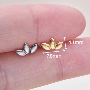 May include: Two small, lotus-shaped earrings. One is silver-colored, the other is gold-colored. The gold earring measures 7.8mm wide and 4.1mm high. The earrings are displayed on a light background.