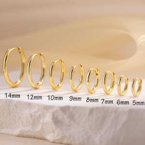 May include: A collection of gold-colored hoop earrings in various sizes, ranging from 5mm to 14mm. Each earring is displayed individually, with the size clearly labeled in millimeters. The earrings have a polished, shiny finish.
