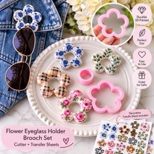 May include: A flower eyeglass holder brooch set featuring multiple flower-shaped holders with various patterns including blue floral, plaid, and pink roses. The set includes a pink 3D printed cutter, a small pink ring, and a sheet of decorative transfer sheets.