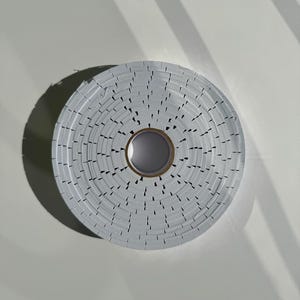 May include: A roll of white adhesive tape with a serrated edge. The tape is wound around a cardboard core.