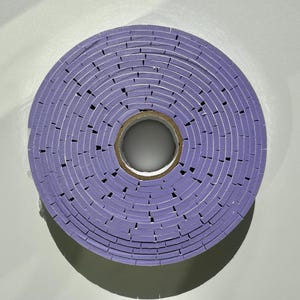 May include: A roll of purple tape wound into a circle. The tape is made of many small squares.