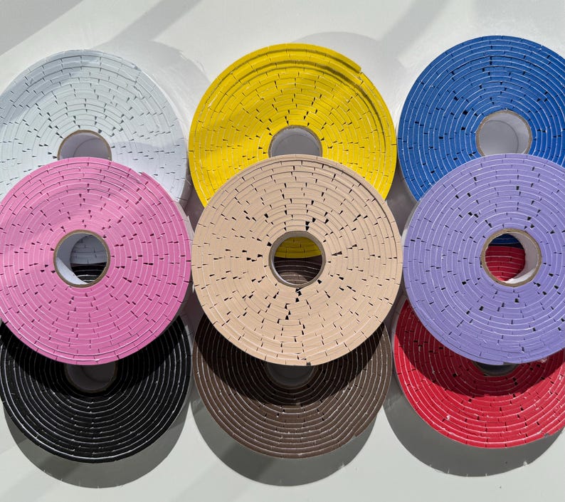 May include: Assortment of colourful round adhesive tape rolls with a patterned design. The rolls are arranged in a circle with the yellow roll at the top.