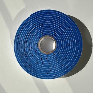 May include: A roll of blue tape with a white core. The tape is wound tightly and has a concentric circle pattern.