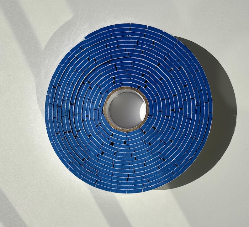 May include: A roll of blue tape with a white core. The tape is wound tightly and has a concentric circle pattern.