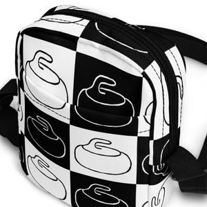 May include: A black and white checkered fanny pack with a repeating pattern of curling stones. The bag has a black zip and strap. The design is a bold, graphic representation of the sport.