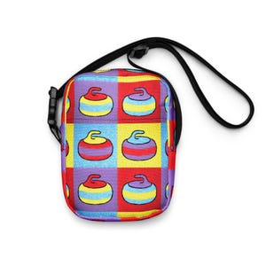 May include: A crossbody bag with a repeating pattern of curling stones on a checkerboard design. The bag has a black adjustable strap and buckle. The curling stones are in red, yellow, blue, and purple. The bag is approximately 20 cm wide.