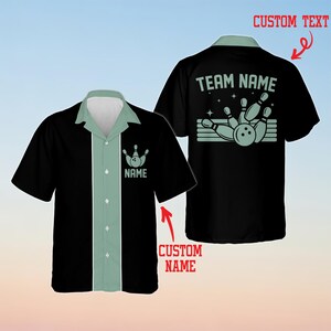 Puede incluir: Una camisa negra de manga corta con botones y un panel vertical verde claro en el centro. La parte delantera presenta un gráfico de bolos y el texto NAME. La parte trasera muestra un gráfico de bolos con el texto TEAM NAME.