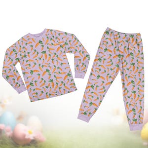 Pode incluir: Um conjunto de pijama roxo claro com um padr&atilde;o repetido de cenouras laranja com folhas verdes. O conjunto inclui uma camisa de manga comprida e cal&ccedil;as a condizer. O pijama &eacute; feito de um material macio.