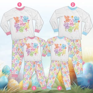 May include: White pajama sets with long sleeves and matching pants. The tops feature colorful bunny graphics with text, and the pants have a repeating bunny pattern. One set has pink trim, the other has blue trim.