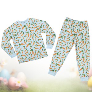 Pode incluir: Um conjunto de pijama azul claro com um padr&atilde;o repetido de cenouras laranja com folhas verdes. O conjunto inclui uma camisa de manga comprida e cal&ccedil;as a condizer. Os punhos e a gola s&atilde;o de um azul claro liso.