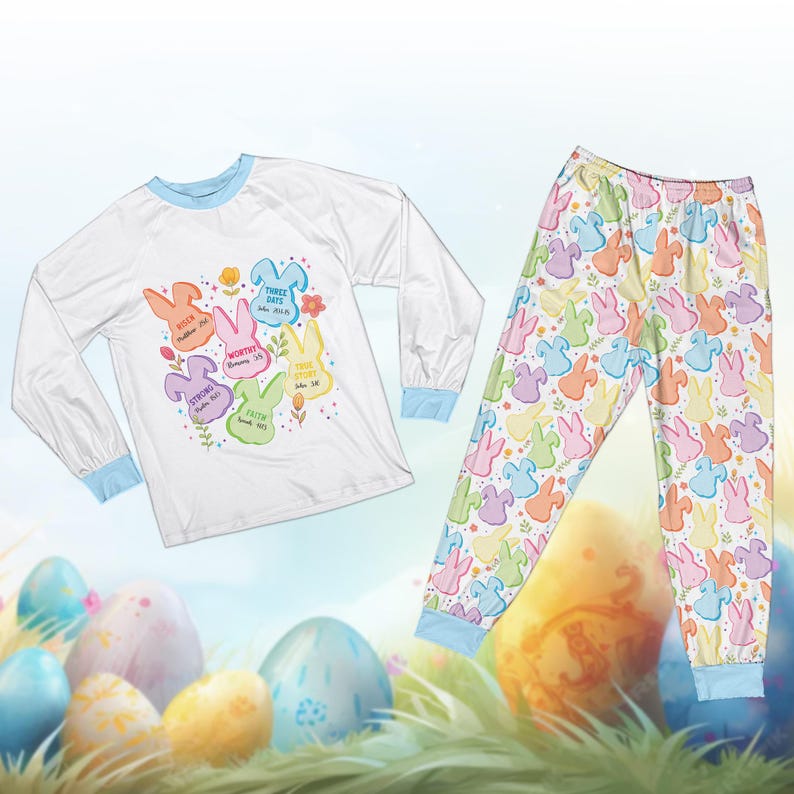May include: White long-sleeve pajama top and matching pants. The top has a blue trim and features colorful bunny shapes with text. The pajama pants have a repeating pattern of pastel-colored bunnies. The pajamas are designed for Easter.