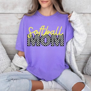 May include: A purple t-shirt with the text "Softball Mom" in yellow and black chequered letters.