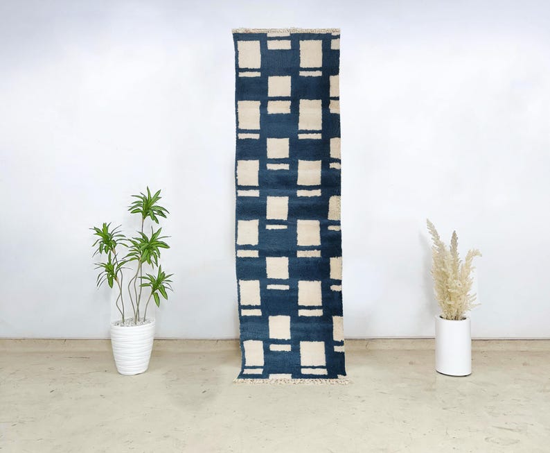 Moroccan wool runner rug featuring a cream square grid pattern on a deep navy blue background, handknotted by Berber artisans. This premium-quality wool rug offers a modern aesthetic with traditional craftsmanship, perfect for entryways, hallways, or kitchens. Its clean geometry, plush texture, and bold contrast make it ideal for contemporary, bohemian, or minimalist spaces seeking authentic Moroccan floor decor with structure and softness.