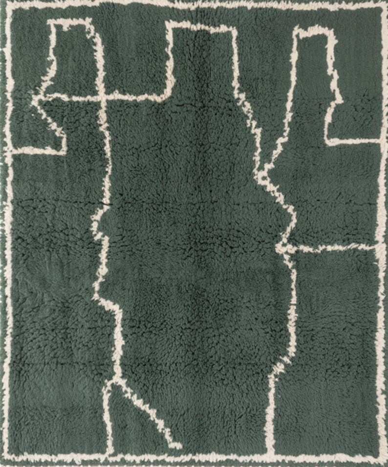 May include: A rectangular, dark green rug with a cream-colored, abstract geometric design. The design features a central shape with linear extensions and a cream-colored border. The rug has a textured, plush appearance.