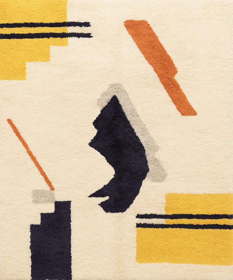 Puede incluir: Alfombra color crema con un dise&ntilde;o abstracto. La alfombra presenta formas geom&eacute;tricas en azul marino, amarillo, naranja y gris. El dise&ntilde;o incluye rect&aacute;ngulos, l&iacute;neas y formas angulares, creando una est&eacute;tica moderna. La alfombra tiene una superficie texturizada.
