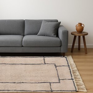 Tan Moroccan wool runner rug featuring a layered double border in charcoal gray. Hand-knotted by Berber artisans in the Beni Ourain style using 100% sheep wool, this soft and thick rug is perfect for long hallways, kitchen walkways, or narrow transitional zones. The modern geometric framing adds symmetry and visual structure to minimalist interiors. A durable, artisan-made wool runner ideal for Japandi, Scandinavian, or contemporary home styling.