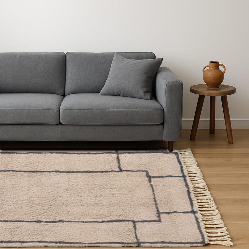 Tan Moroccan wool runner rug featuring a layered double border in charcoal gray. Hand-knotted by Berber artisans in the Beni Ourain style using 100% sheep wool, this soft and thick rug is perfect for long hallways, kitchen walkways, or narrow transitional zones. The modern geometric framing adds symmetry and visual structure to minimalist interiors. A durable, artisan-made wool runner ideal for Japandi, Scandinavian, or contemporary home styling.