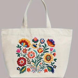Peut inclure: Sac fourre-tout crème or blanc cassé avec un motif floral coloré. Les fleurs brodées présentent des couleurs vives, notamment le rouge, le jaune, le bleu et le rose, sur des feuilles vertes. Le sac a deux anses.