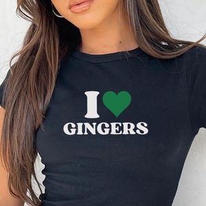 Może przedstawiać: Czarny t-shirt z napisem "I ♥ GINGERS" białymi literami i zielonym sercem. Koszulka jest krótka i dopasowana.