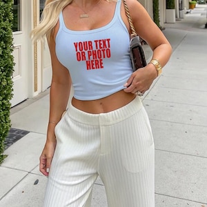 May include: A light blue ribbed tank top featuring the red text "YOUR TEXT OR PHOTO HERE" on the front, paired with white ribbed wide-leg trousers. The tank top has a scoop neckline and a cropped fit, while the trousers feature a high-waisted design.