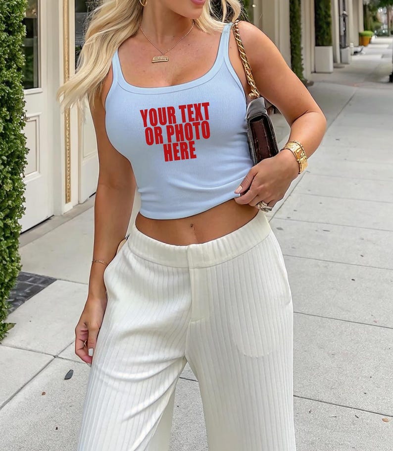 May include: A light blue ribbed tank top featuring the red text "YOUR TEXT OR PHOTO HERE" on the front, paired with white ribbed wide-leg trousers. The tank top has a scoop neckline and a cropped fit, while the trousers feature a high-waisted design.