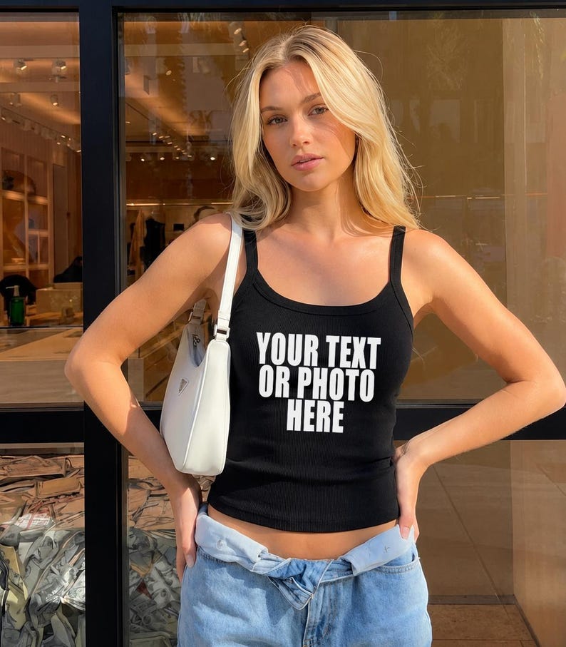 May include: A black ribbed tank top featuring the white text YOUR TEXT OR PHOTO HERE printed on the front, paired with a white shoulder bag and light blue denim jeans. The tank top has a scoop neckline and wide shoulder straps.