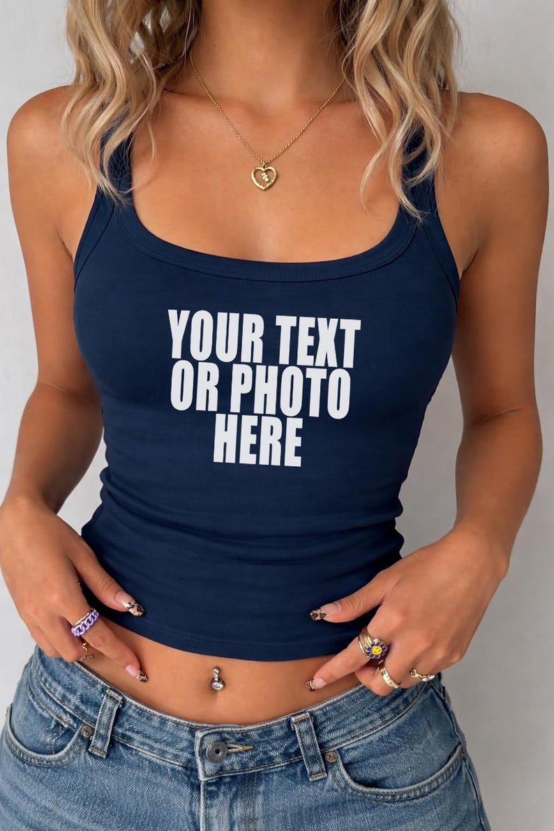 May include: A dark navy blue sleeveless tank top with a scoop neckline. The front of the garment features the white printed text "YOUR TEXT OR PHOTO HERE" centered on the chest. The top is paired with blue denim jeans.