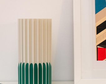 May include: A white and green cylindrical table lamp with a fluted design. The bottom half of the lamp is green with a rounded edge.