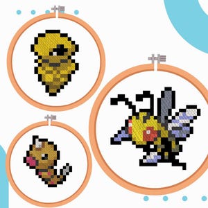 Puede incluir: Tres aros de bordado de punto de cruz con imágenes pixeladas de Pokémon. El aro superior muestra una criatura amarilla y marrón en forma de capullo. El aro inferior izquierdo muestra una criatura marrón en forma de gusano. El aro más grande a la derecha muestra una criatura amarilla y negra con forma de abeja.