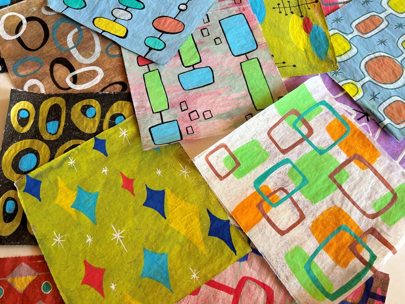 May include: A selection of patterned paper squares with mid-century modern designs. The squares display geometric shapes, including diamonds, rectangles, and circles, in various colours like blue, green, yellow, and orange. Some have starburst accents.