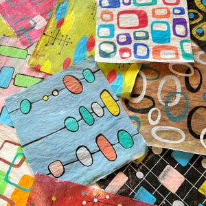 May include: A selection of colourful, patterned paper squares with mid-century modern designs. The squares feature geometric shapes in various colours, including red, blue, yellow, and green. Some have atomic-age inspired designs, while others have abstract patterns.