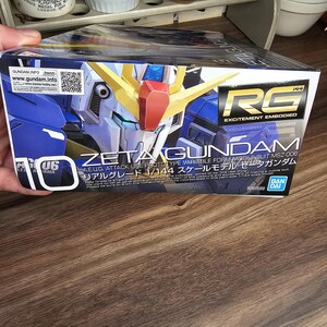 May include: A box for a Zeta Gundam model kit. The box is primarily blue with images of the robot and text in English and Japanese. The box also has the text "RG EXCITEMENT EMBODIED".