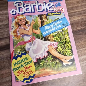 Puede incluir: Una portada de revista Barbie vintage con borde rosa. La portada presenta una ilustración de dibujos animados de Barbie en un columpio, con el texto "Happy Easter everyone love... Barbie." La revista también menciona "Rock Star Jon Bon Jovi."