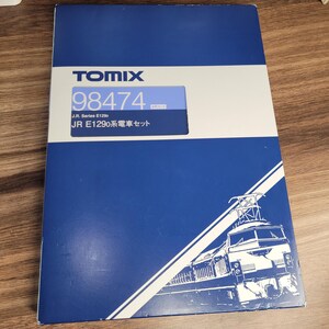 Puede incluir: Una caja azul con texto blanco y un contorno blanco de un tren. El texto en la caja dice "TOMIX 98474 J.R. Series E129c JR E129系電車セット".
