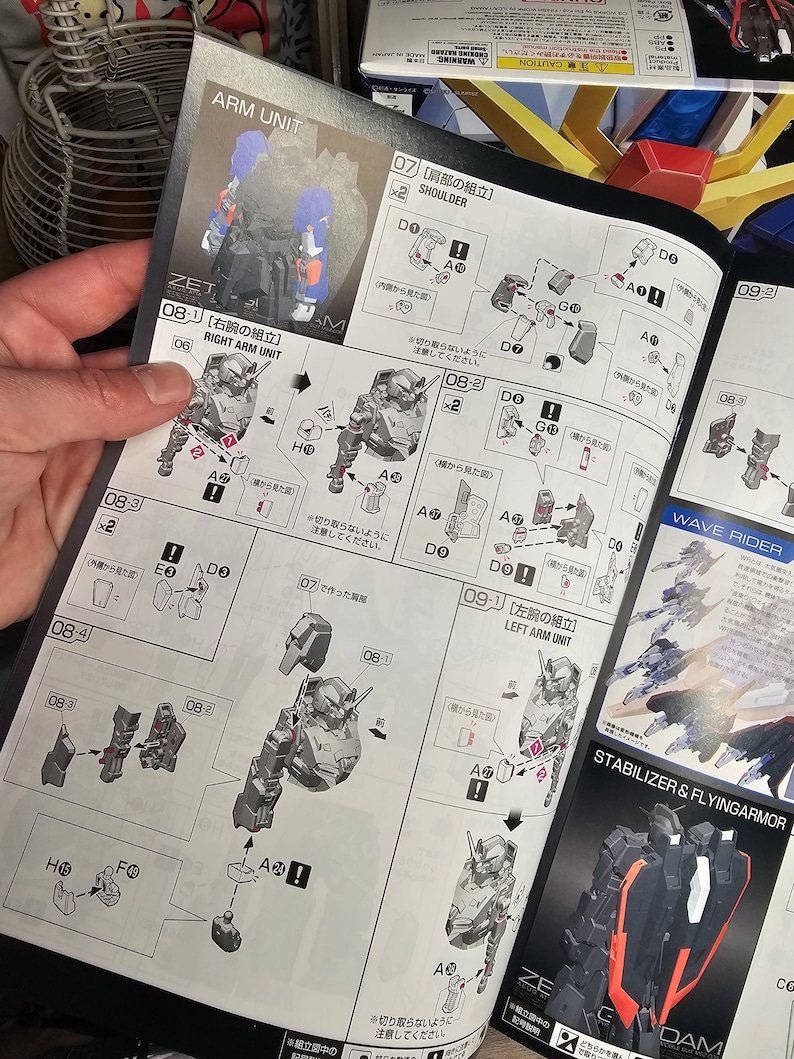 May include: Open instruction manual for a ZET Gundam model kit, featuring detailed diagrams for assembling the arm unit and shoulder components. The manual includes Japanese text and illustrations of the model's parts.