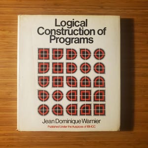 May include: A vintage book titled "Logical Construction of Programs" by Jean Dominique Warnier. The cover features a geometric design in red and black. Published under the auspices of IBI-ICC.