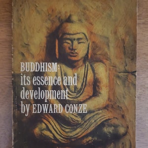 May include: A book cover with a painting of a Buddha statue in a seated meditation pose. The book title is "Buddhism: its essence and development" by Edward Conze. The book is a Harper Torchbook, number 58, and costs $1.35.