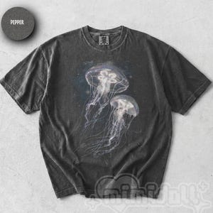 May include: A charcoal grey short-sleeve t-shirt featuring a graphic print of two translucent jellyfish floating against a dark, starry background. The shirt has a crew neckline and a vintage-style washed finish. A small circular patch reads Pepper.