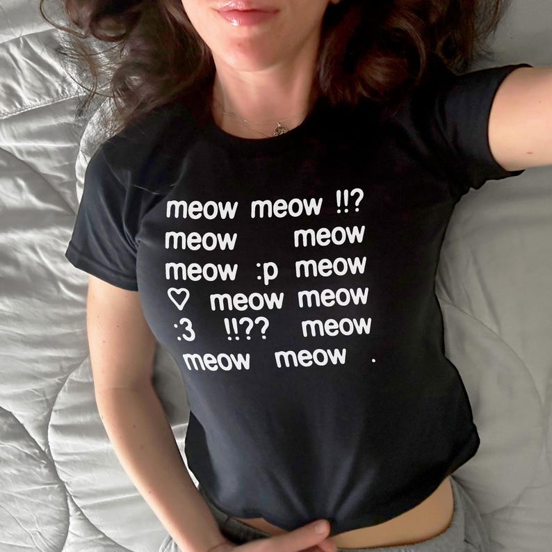 May include: Black t-shirt with the text "meow meow !!? meow meow meow :p meow meow meow :3 !!?? meow meow meow ." in white. The shirt is a crew neck style.
