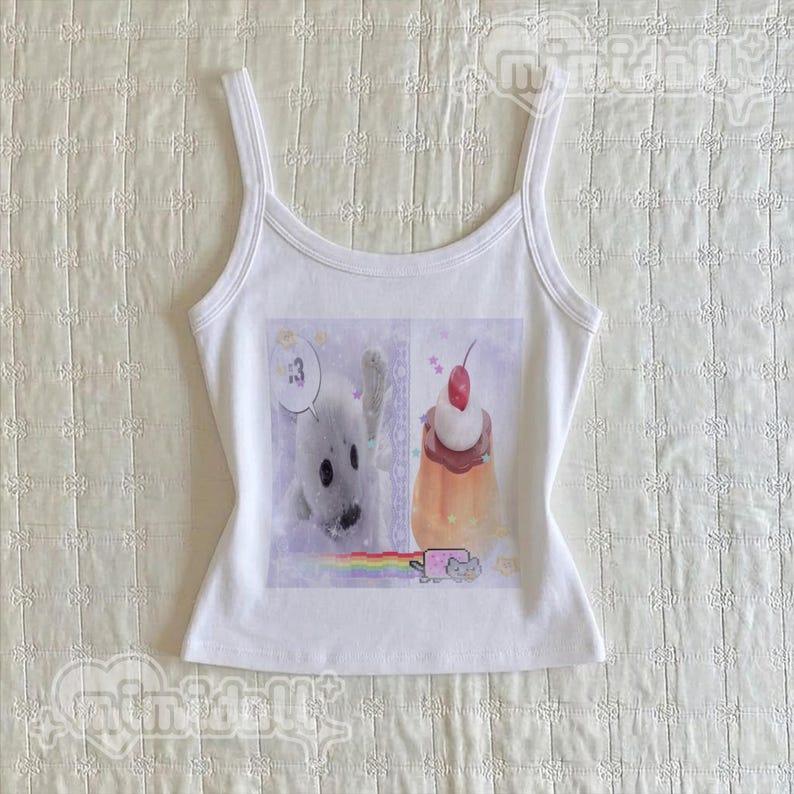 May include: A white sleeveless tank top featuring a central graphic print. The image displays a white seal, a dessert topped with a cherry, a small cat icon, and a rainbow. The text :3 is visible in a speech bubble above the seal.