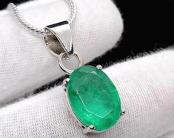 May include: A silver pendant necklace featuring a vibrant green oval-cut gemstone. The gemstone is set in a silver bezel and hangs from a delicate silver chain. The pendant is displayed against a white background.