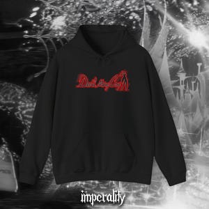 Puede incluir: Sudadera negra con bolsillo delantero y capucha con cordón. La sudadera presenta el texto rojo "Devil May Cry" con un gráfico de silueta. La palabra "imperality" está impresa en blanco en la parte inferior.
