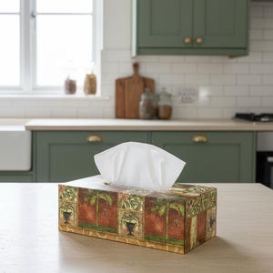 May include: A black Smeg stand mixer with a stainless steel bowl and a rectangular tissue box cover featuring a decorative pattern of green palm trees and urns on a red and gold background with white tissues protruding from the top opening.