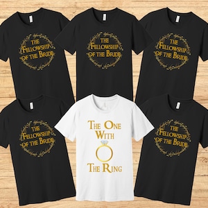 May include: Set of six black t-shirts with gold lettering. The shirts feature the text "The Fellowship of the Bride" and "The One with the Ring".