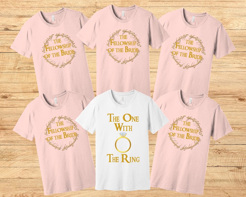 May include: Set of six pink t-shirts with gold text and graphics. The shirts feature the text "The Fellowship of the Bride" and "The One with the Ring".