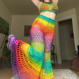 Könnte beinhalten: Ein Regenbogen-Crochet-Top und eine passende Hose. Das Top ist ein Halfter-Stil mit einem Kreuz-Design an der Vorderseite. Die Hose ist weit geschnitten und hat einen ausgestellten Saum.