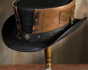 May include: A black and brown leather top hat with a lace-up detail and a gear accent. The hat is on a wooden stand.