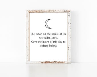 May include: A white framed print with a black crescent moon and a poem about the moon shining on new fallen snow. The poem reads: "The moon on the breast of the new fallen snow, Gave the lustre of mid-day to objects below;"